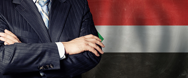Male hands against Sudanese flag background, business, politics and education in Sudan concept