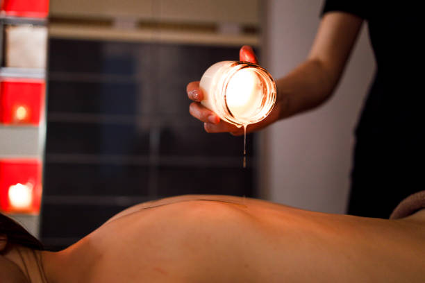 masseur masse le client avec une bougie fondue - bougie de massage photos et images de collection