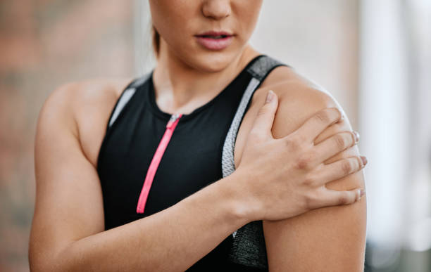 istock Unknown trainer alone in gym and suffering from shoulder injury. One coach standing and rubbing arm during workout in exercise health club. One woman in fitness centre feeling pain in routine training 1401914164