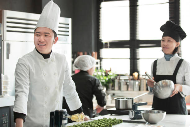young chinese pastry chefs talking and laughing - stock photo - chef’s utensils imagens e fotografias de stock