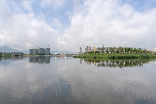 The lake reflects the city skyline in cloudy weather