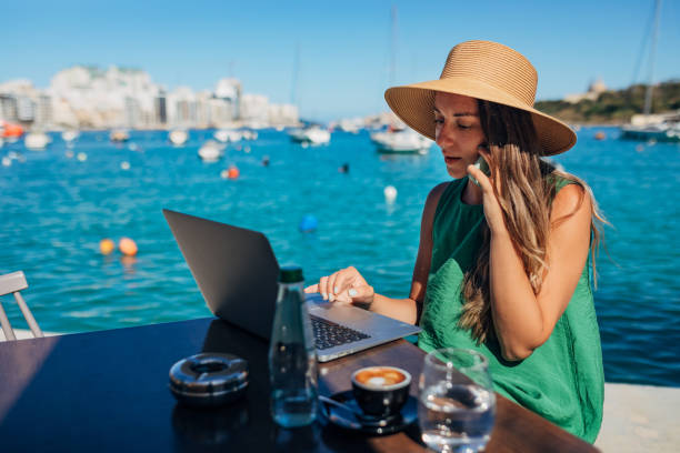 istock A woman with a straw hat makes a phone call while working remotely sitting in a coffee shop by the sea 1401918692