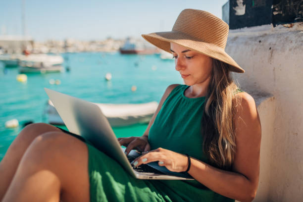 istock A millennial woman with a straw hat works remotely while enjoying a vacation at sea 1401918764