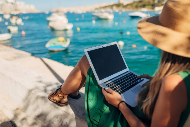 istock Rear view of a woman enjoying sea and harbor views while working remotely using a laptop 1401918780