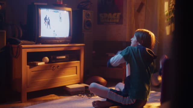 Nostalgic Retro Childhood Concept. Young Boy Watches Hockey Match on TV in His Room with Dated Interior. Supporting His Favorite Team, Getting Excited When Players Score a Goal.