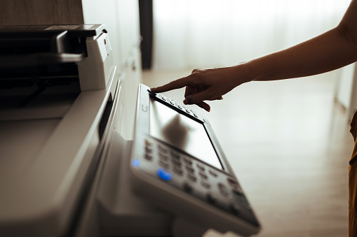 Businesswoman making copies with copy machine at office