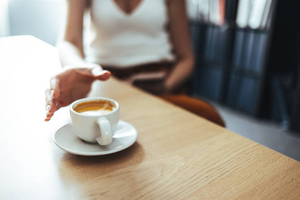 le mani della signora che raggiungono la tazza di caffè - brown candid caffein drink foto e immagini stock