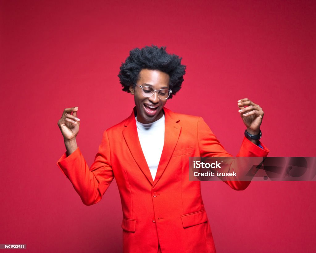 Businessman enjoying dance Happy businessman in red blazer dancing against colored background Dancing Stock Photo