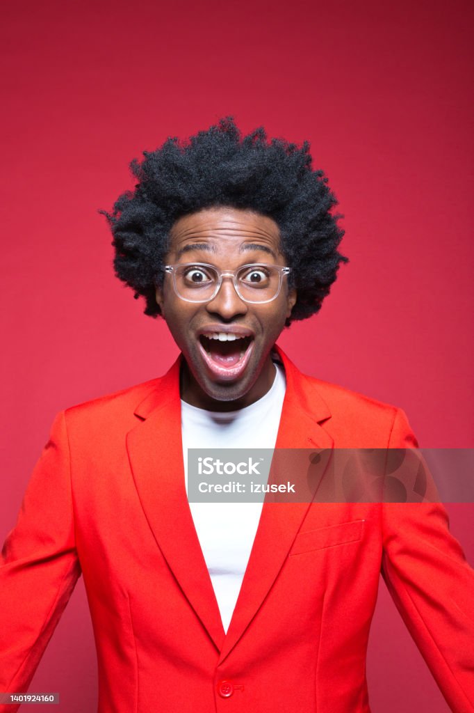 Businessman in red blazer with mouth open Portrait of cheerful businessman with Afro hairstyle standing against red background Colored Background Stock Photo