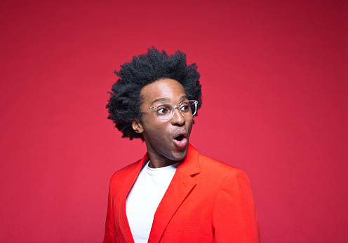 Businessman with mouth open wearing red blazer against colored background