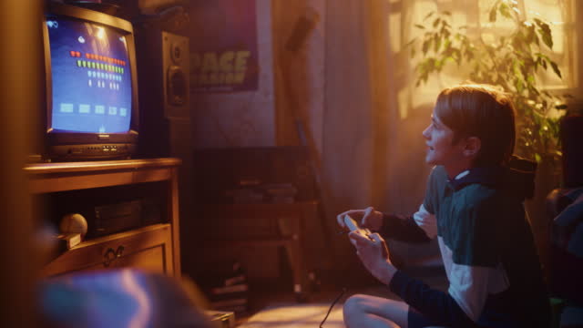 Young Boy Playing Eighties 2D Arcade Space Shooter Video Game on a Console at Home in His Room with Old-School Interior. Child Successfully Wins the Level. Nostalgic Retro Childhood Concept.
