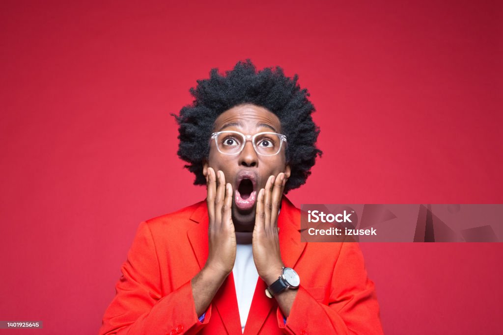 Businesswoman with hand on chin Surprised businessman with hand on chin wearing red blazer against colored background Surprise Stock Photo