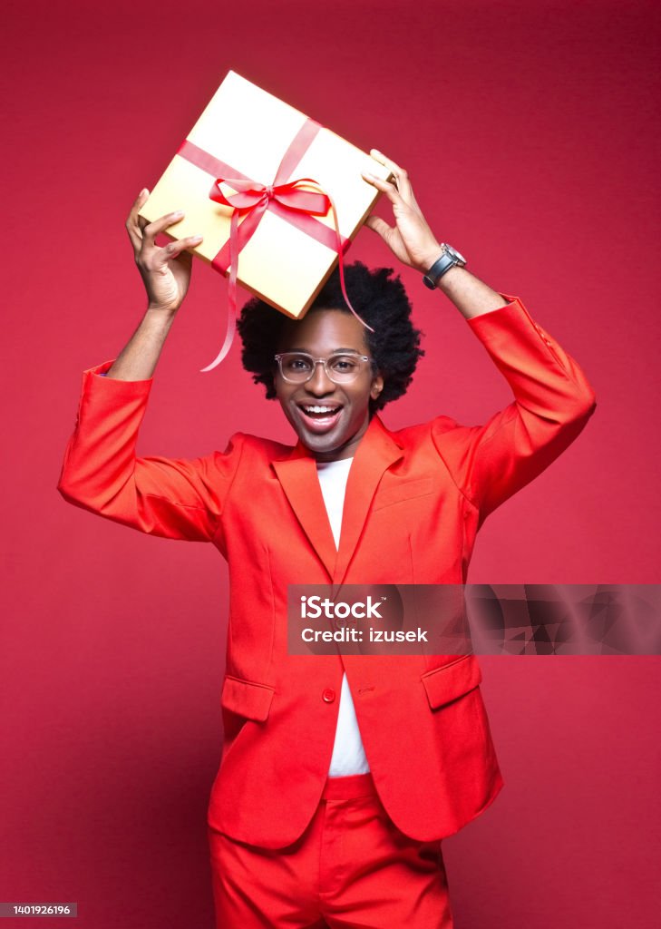 Happy businessman holding gift box Portrait of smiling businessman holding gift box while standing against red background Gift Stock Photo