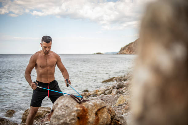 A young handsome man with pronounced muscles exercising on the seashore.