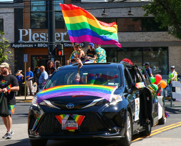 Large rainbow flag sticking out from car during the Gay Pride car parade stock photo