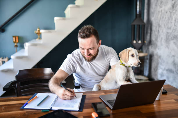 istock Funny Dog Works On Laptop While Owner Writes Down Tasks In Notebook 1401933528