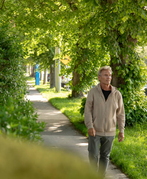 istock Mature man walks along residential sidewalk 1401938186