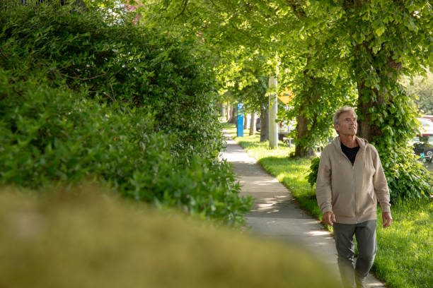Mature man walks along residential sidewalk