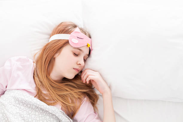 istock Sleeping girl wearing funny  eyemask lying in a bed under a blanket. 1401938497