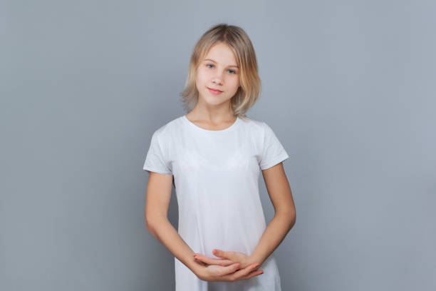 fröhliches teenager-mädchen im alter von 10-12 jahren posiert vor einer grauen wand. - 12 13 years stock-fotos und bilder