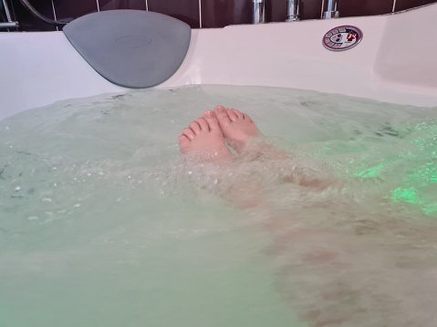 Children feet and relaxing massage in hot tub. Closeup of playful and joyful female legs