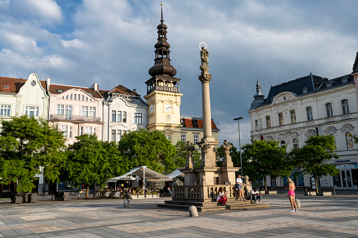 The central square of the city of Ostrava - Masaryk Square. People hang out around the Marian Column, in the background, the building of the Ostrava Museum.