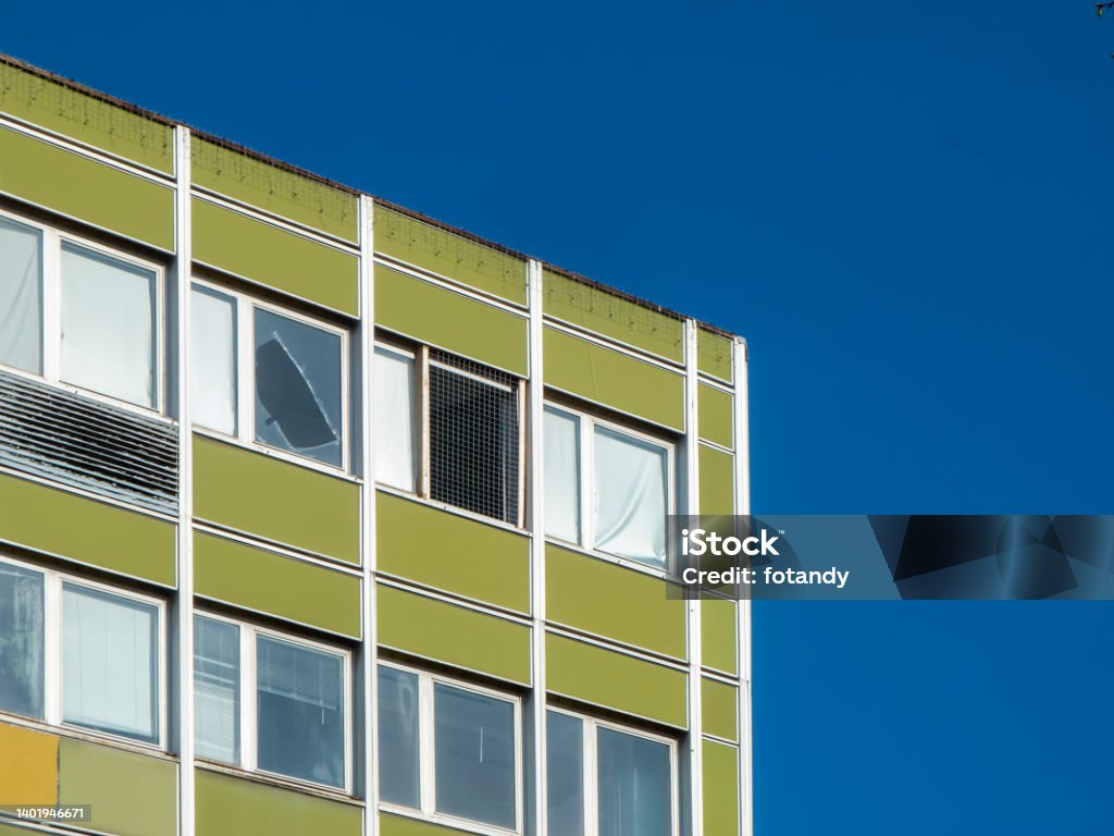 Window panes in the office building Partial view of a corner of an office building near the roof with a defective window pane against a blue sky. Architecture Stock Photo