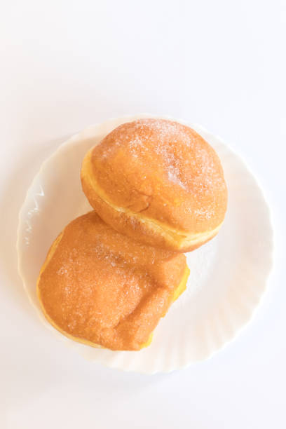 Bolas de Berlim, Berliner or donuts filled with egg jam. A very popular dessert in Portuguese pastry shops. Two bolas de berlim on a plate.