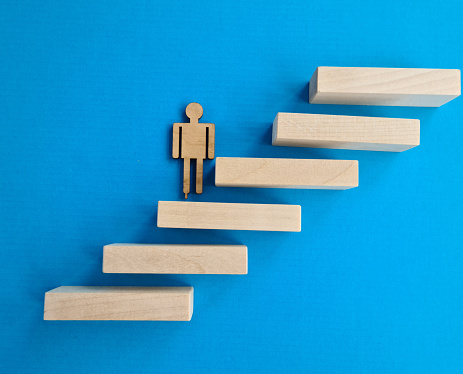 Miniature figure of man climbs staircase along wooden bars. Career success and goal achievement concept