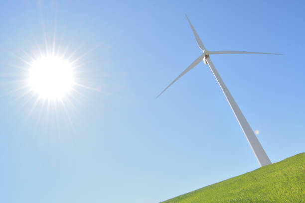 太陽が輝き、青空を持つ緑のフィールドで再生可能エネルギーの風力タービン - eolo ストックフォトと画像