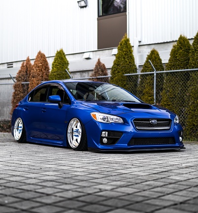 Bellevue, WA, USA\n5/2/2022\nBlue Subaru WRX with Work Meister Wheels viewed from the side with small trees in the background