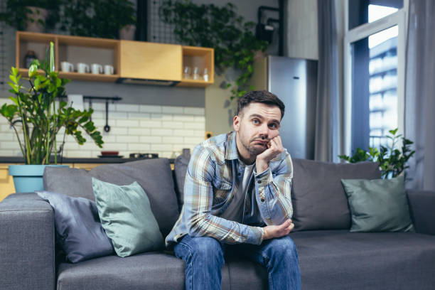 istock Sad and pensive man sitting on the couch at home 1401950134