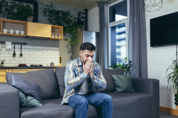 istock A sick man at home sitting on the couch has a cold cough and runny nose 1401950155
