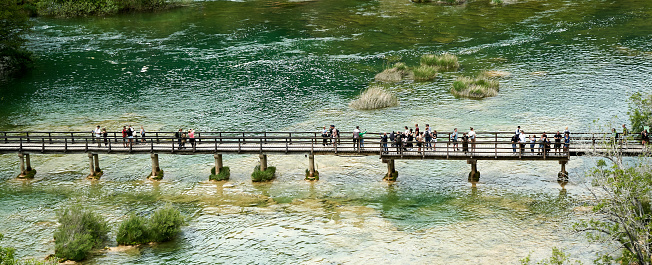 Krka, Croatia, May 2, 2022: Bridge with tourists and visitors of a park looking at the lake and the river