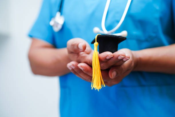 Asian woman doctor holding graduation hat in hospital, Medical education concept. stock photo