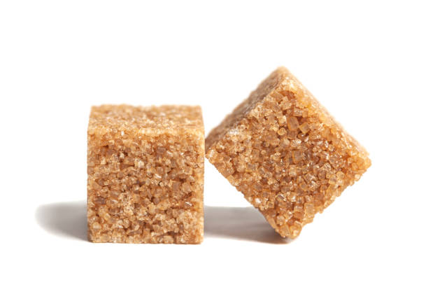 две части коричневых кубиков тростникового сахара выделены на белом фоне - turbinado sugar стоковые фото и изображения