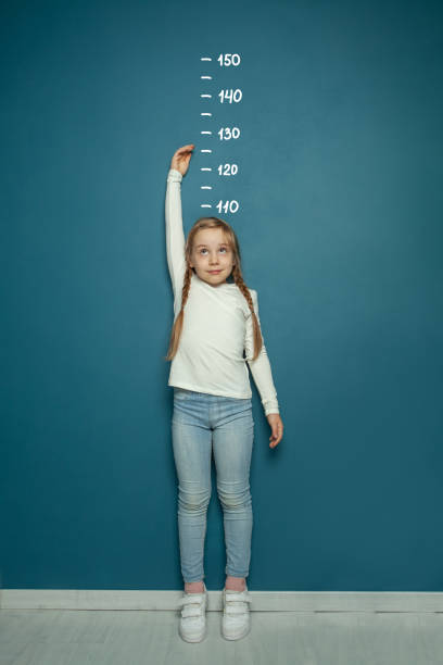 child girl measuring the growth on the background of wall at home. girl power concept. - kort längd bildbanksfoton och bilder
