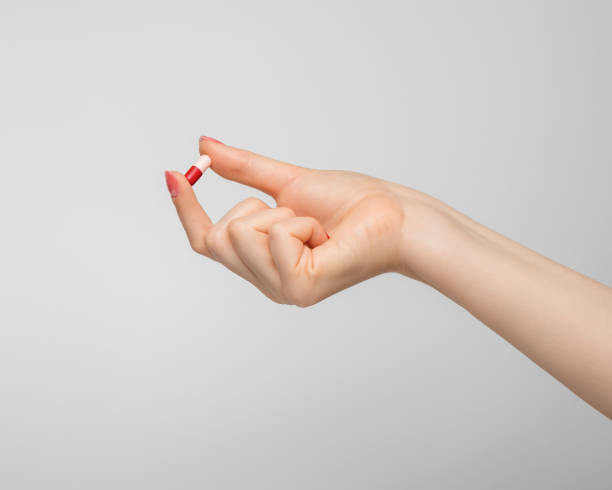 istock Tablet in a capsule in a woman's hand on gray background. 1401959901