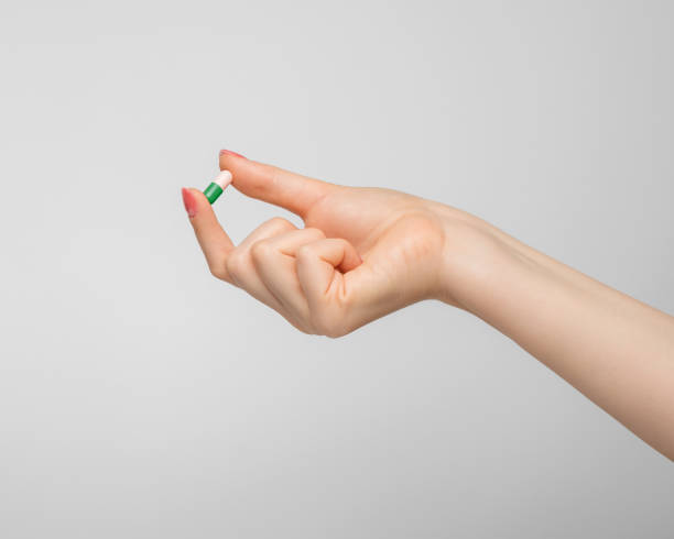 istock Tablet in a capsule in a woman's hand on gray background. 1401959902