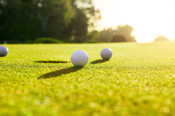 istock Three golf balls on the green grass near hole on a golf course at sunset 1401960993