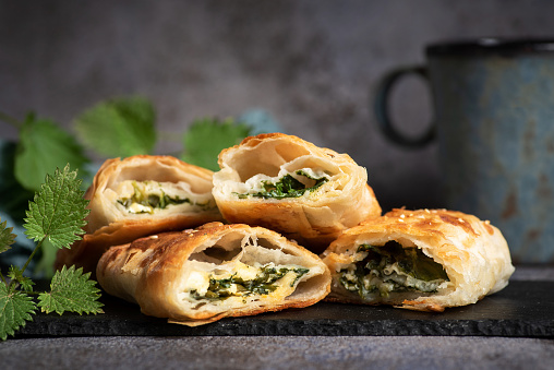 Freshly baked rolled pie with organic nettles on black-gray background