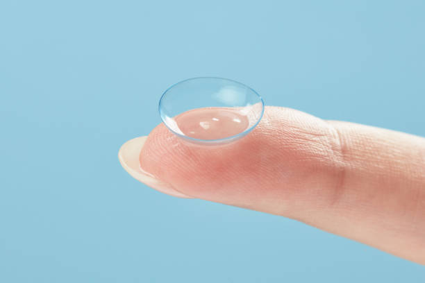 istock Contact lens on finger on blue background. 1401964240