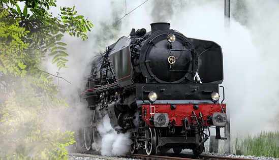 Vintage model electric train formed by a steam locomotive and green passenger cars on the rails