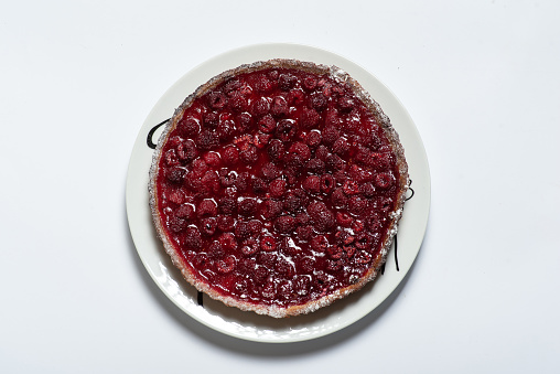 Close up of a strawberry, raspberry crumble pie. The pie is in a blue and white pie dish, and a spoon is just scooping out some of the pie.
