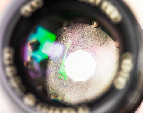 Close-up looking through the glass of a camera lens, with the variable aperture visible.