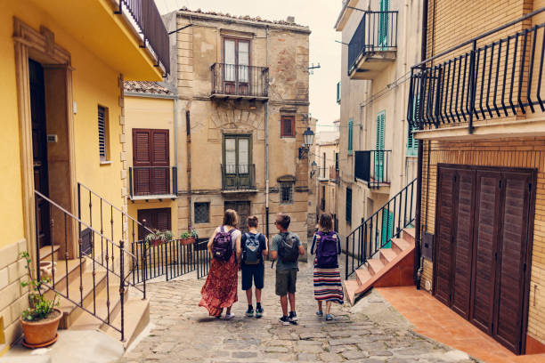 mother and teenagers walking in the streets of italian town - camel back imagens e fotografias de stock