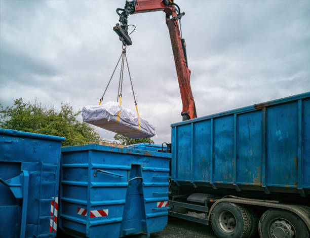 Crane truck with asbestos bag being reloaded into another container at a recycling yard. stock photo