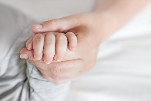 Hand of sleeping baby in the hand of mother. Newborn baby with mom. Motherhood care and baby care. copy space