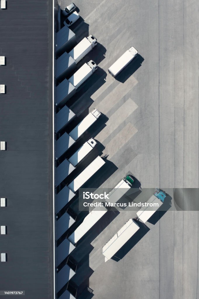 Trucks at the loading bay of a warehouse View from above of a distribution warehouse with loading docks and various trucks. Truck Stock Photo