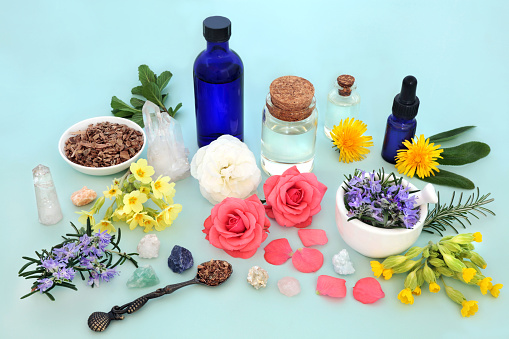 Herb and flower ingredients for alternative medicine treatments. Natural pagan traditional health care remedy with essential oils, crystals. Esoteric alchemy wiccan concept. On blue background.